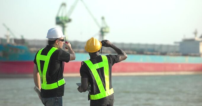Engineer and technician review port operations and coastal logistics beside the waterfront in daylight, supporting maritime planning, cargo monitoring, and harbor infrastructure assessment.
