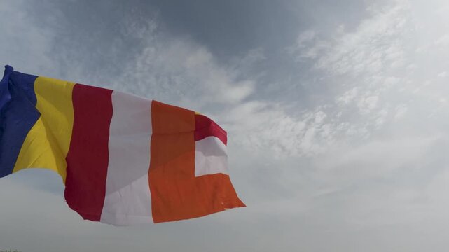 Buddhist Prayer Flag in the Wind: A vibrant Buddhist prayer flag dances in the wind against a dramatic sky, symbolizing peace, compassion, and the spread of positive energy.