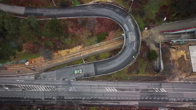 Aerial view of rally car racing through sharp hairpin turn near Strahov Stadium in Prague during autumn