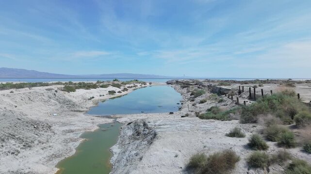Low drone shot flying forward just above the water through the marina basin at Desert Shores, California, moving toward the Salton Sea.