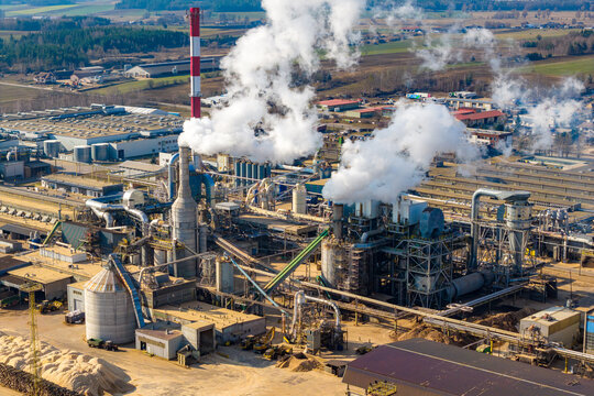 Aerial view of a large industrial complex showing a wood processing factory with multiple chimneys emitting white smoke, Grajewo, Podlaskie Voivodeship, Poland.