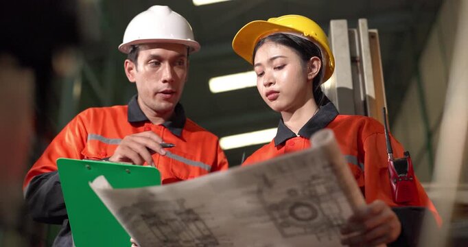 Technicians review an engine parts blueprint and production drawing beside a machine control station in a manufacturing facility, showing planning, supervision, and process verification.
