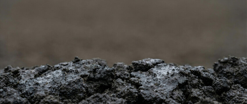Wet mud texture in dark tones with puddles after rain