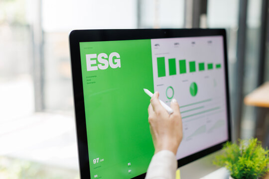 Asian Professionals Reviewing "Building a Sustainable Future" Report Analyzing Environmental Impact Data and Green Dashboard  in Modern Office