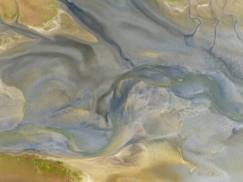 Aerial view of a landscape with intricate patterns of winding waterways cutting through the sand, creating a mosaic of textures and tones, Walvis Bay, Erongo Region, Namibia.