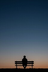 Obraz premium Silhouette of a Contemplative Figure on a Park Bench at Dusk with Expansive Twilight Sky