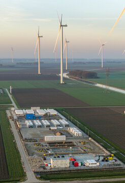 Aerial view of a large scale energy storage system with numerous wind turbines generating renewable power in a rural landscape