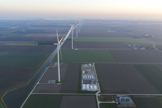 Aerial view of a wind farm generating renewable power, connected to a large battery energy storage system