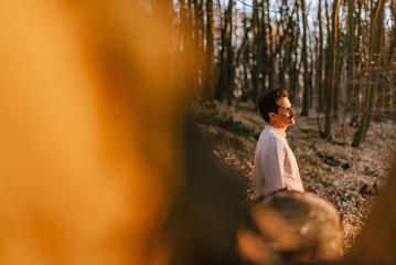 Fototapeta premium Young Man in Sunlit Forest Reflecting on Mental Health