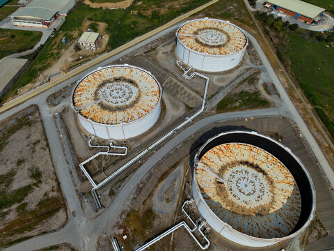 Aerial view of colossal tanks, their white surfaces aged with rust, stand as silent sentinels against the backdrop of Thessaloniki, Greece.