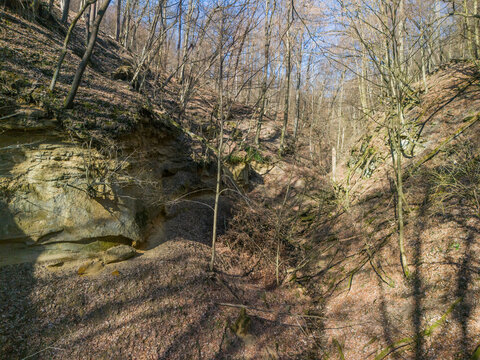 Aerial view of sunlight casting shadows on the rugged terrain of Cerova vrchovina, highlighting the textures of rock and sparse vegetation, Mucin, Banska Bystrica Region, Slovakia.