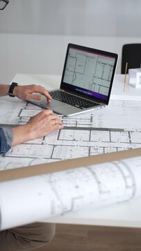Architect drawing and measuring blueprints on a desk, creating detailed floor plans and designs for construction projects, demonstrating precision and expertise in architectural planning