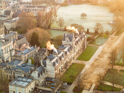 Aerial view of Magdalen College's grand architecture stands majestically amidst manicured lawns and the serene River Cherwell, a timeless scene bathed in soft light, Oxford, England, United Kingdom.