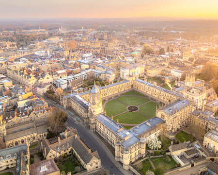 Aerial view of the golden-hued quadrangle of Christ Church College basks in the soft, ethereal glow of sunset, casting long shadows across Oxford's ancient streets, Oxford, England, United Kingdom.
