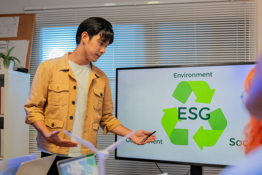 Business team analyzing ESG strategy with presentation on sustainability, renewable energy, and corporate responsibility, discussing data, environmental impact, and green innovation in modern office m