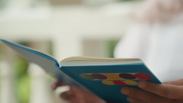 Balcony study with tropical ambiance. Relaxed student flipping pages on tropical island balcony. Student concentrates on reading book amidst gentle tropical breezes and shaded surroundings