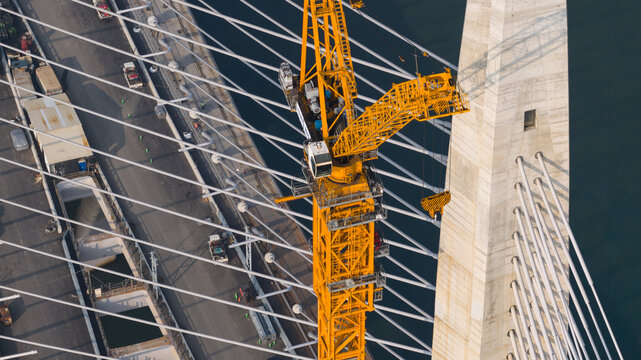 Aerial view of the Tamsui-Tamsui Bridge under construction, a symphony of concrete and steel reaching for the sky above the tranquil waters, New Taipei City, Taiwan.