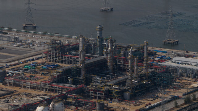 Aerial view of industrial complex with towering structures against the backdrop of the sea, Tambon Map Ta Phut, Chang Wat Rayong, Thailand.