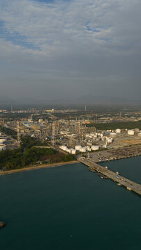Aerial view of industrial complex with storage tanks and processing units meet the blue sea, Map Ta Phut, Chang Wat Rayong, Thailand.