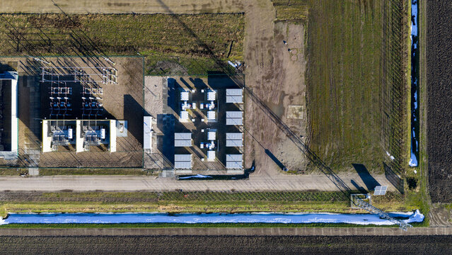 Aerial view of geometric structures casting stark shadows on the flat landscape, juxtaposed with agricultural fields, Zeewolde, Flevoland, Netherlands.