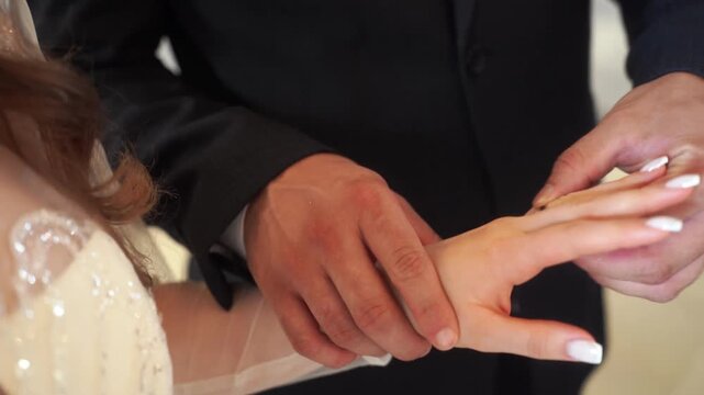 Closeup the intimate moment of bride and groom exchanging wedding diamond rings during wedding ceremony. Beautifully symbolizes love, commitment, and beginning of lifelong journey together