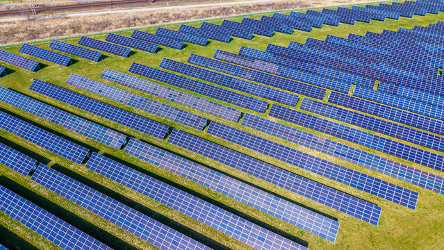 Aerial view of solar panels standing in rows on the grass field reflecting the sky, in the fields of Sevetin, Sevetin, South Bohemian Region, Czechia.