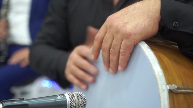 Close-up of a man playing a drum at an Armenian wedding. Wedding band, tradition