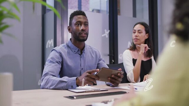 Man glancing and leading business meeting, referencing tablet, animated letters appearing around it