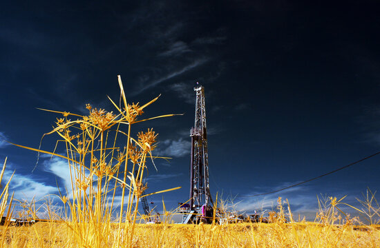 Onshore drilling rig under a blue sky with yellow grass in the foreground