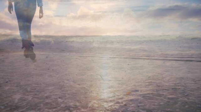 Walking female in fitted jeans, ankle boots moving along wet shoreline, sun reflection, copy space