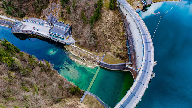 Aerial view of the imposing Staudamm Klaus dam with its concrete face contrasting against the vibrant turquoise lake, nestled in lush green forests, Klaus an der Pyhrnbahn, Oberosterreich, Austria.