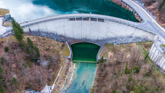 Aerial view of the imposing Staudamm Klaus dam reflects the sky in its reservoir, a stark contrast to the surrounding forests, Klaus an der Pyhrnbahn, Oberosterreich, Austria.