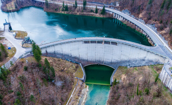Aerial view of the concrete dam wall holding back the tranquil, dark waters of the reservoir, contrasting with the surrounding autumn foliage, Klaus an der Pyhrnbahn, Oberosterreich, Austria.