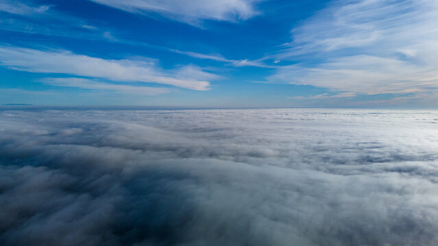 Aerial view of a sea of fluffy clouds stretching to the horizon under a bright blue sky, Malibu, California, United States.