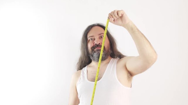 Man measuring beard with tape measure against plain white background, playful and humorous self-portrait.