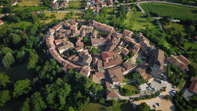 Aerial view of the ancient walled city with its tightly packed terracotta roofs and surrounding verdant trees, Perouges, Auvergne-Rhone-Alpes, France.