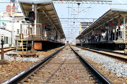 鉄道駅のホームで電車を待つ人々と線路の風景　社会インフラと日常の通勤、期待と接続を象徴するコンセプトイメージ