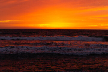 Fototapeta premium Bright Orange Sunset Over Pacific Ocean Waves California