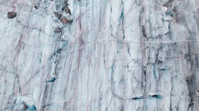 Aerial close‑up of the Aletsch Glacier&rsquo;s textured ice surface, showing deep crevasses, blue meltwater pockets, and dramatic glacial patterns in the Swiss Alps by drone 4k.