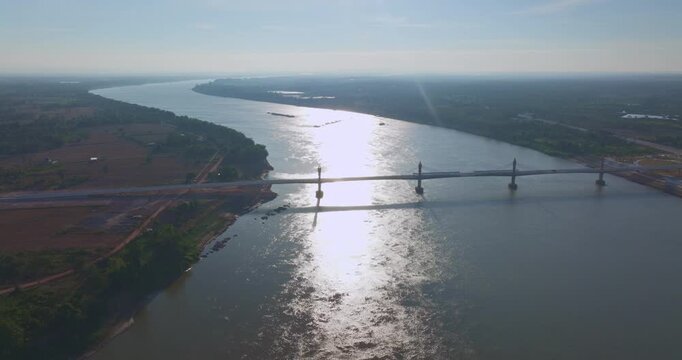 High angle drone shot of a landmark bridge connecting two nations, emphasizing engineering design, mobility, and economic progress in Southeast Asia.