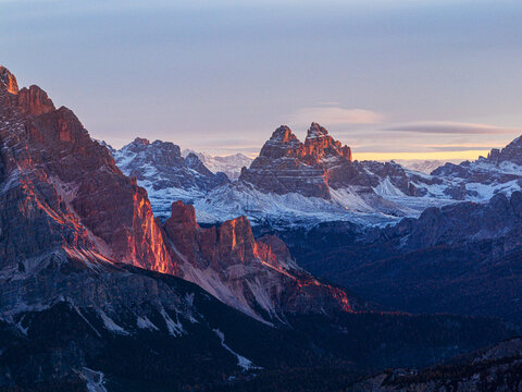 Aerial view of the Tre Cime di Lavaredo peaks ablaze with the rising sun's fiery hues, Dolomites, Italy.
