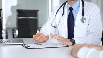 Male doctor communicating with patient at a clinic desk, offering professional healthcare guidance...