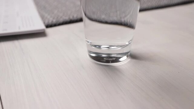 hand places pill organizer and water on table, medication adherence routine concept