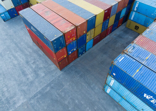 Aerial view of stacked, vibrant shipping containers in a port, their hues contrasting against the stark concrete, creating a geometric tableau, Figueira da Foz, Coimbra District, Portugal.