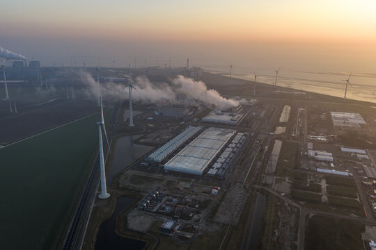 Aerial view of hyperscale data center operating with steam cooling, generating artificial intelligence and large data, powered by many wind turbines