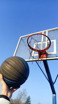 Close-up of basketball player holding ball while standing against blue sky. Success, scoring, winning and achieve the goal concept
