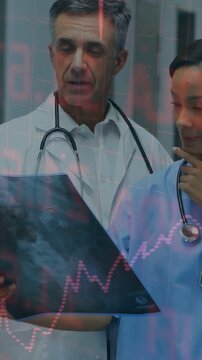 Vertical video: Doctor holding scan, reviewing, nurse adjusting steth, pink charts moving across