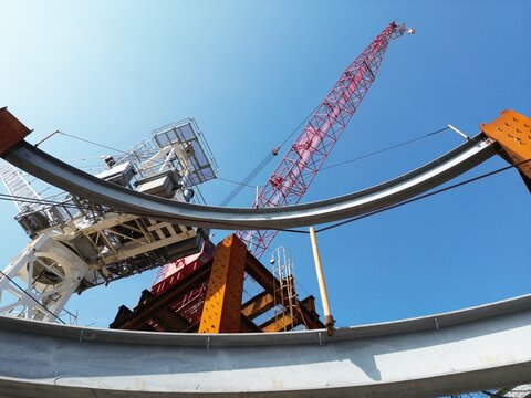 Curved steel beams and tower cranes at a construction site.