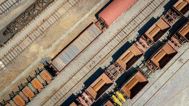 Aerial view of freight trains and rail tracks create geometric patterns of rust and steel, casting long shadows in the afternoon sun, Vila Nova de Gaia, Porto District, Portugal.