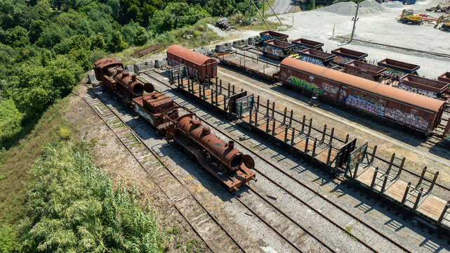 Aerial view of rusted trains, weathered railcars, and verdant foliage create a scene of industrial decay, Vila Nova de Gaia, Portugal.